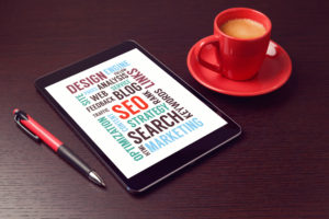 Digital tablet with seo words and coffee cup on office desk